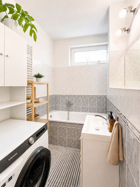 Badezimmer mit Dusche, Badewanne und Waschmaschine in einer 4-Zimmer-Wohnung.