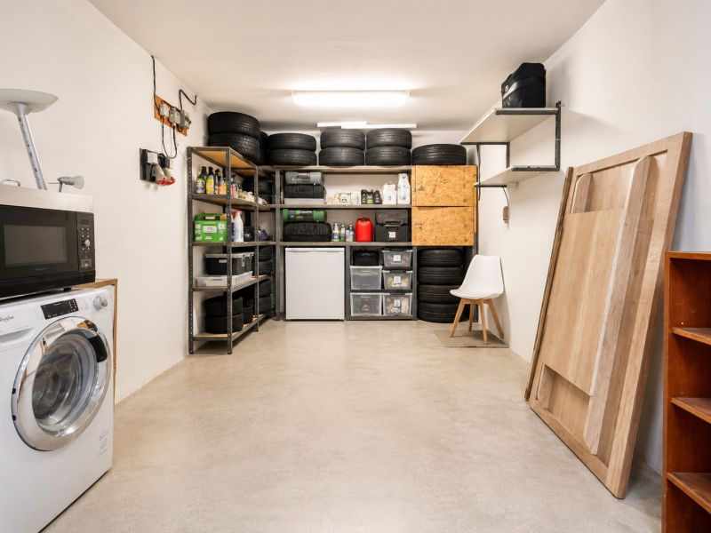 Der Hauswirtschaftsraum in der Vierzimmerwohnung enthält eine Waschmaschine, eine Mikrowelle und Lagerregale.