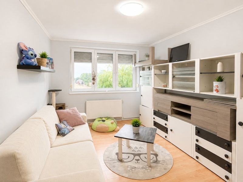 Wohnzimmer in einer 4-Zimmer-Wohnung mit Holzboden und einem Regal mit Dekorationen.