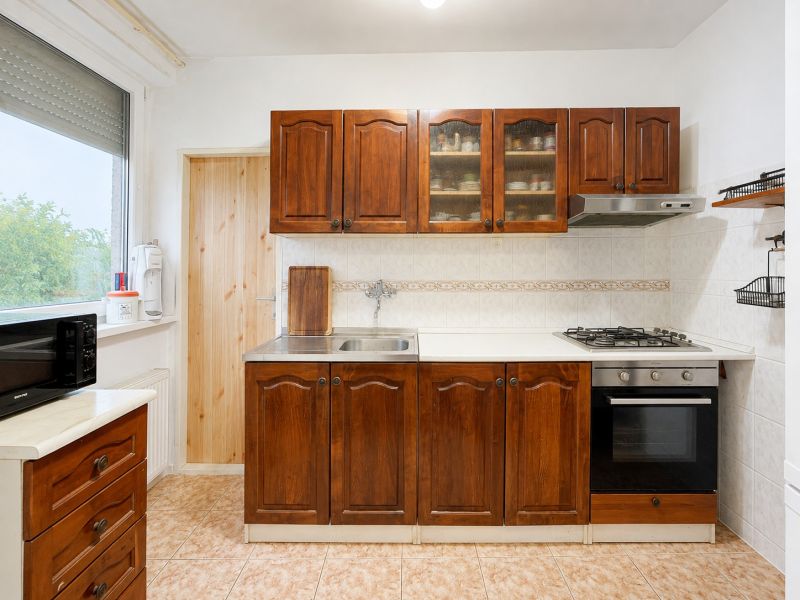 Küche mit Holzschränken und Fliesenboden in einer Vierzimmerwohnung.