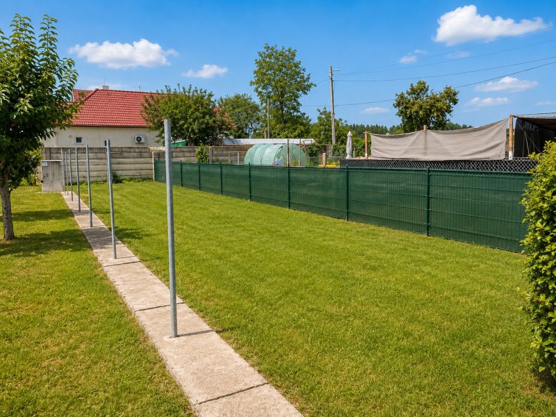 Ein Garten mit Rasen und Gehweg in einer 4-Zimmer-Wohnung in Jahodná an einem sonnigen Tag.