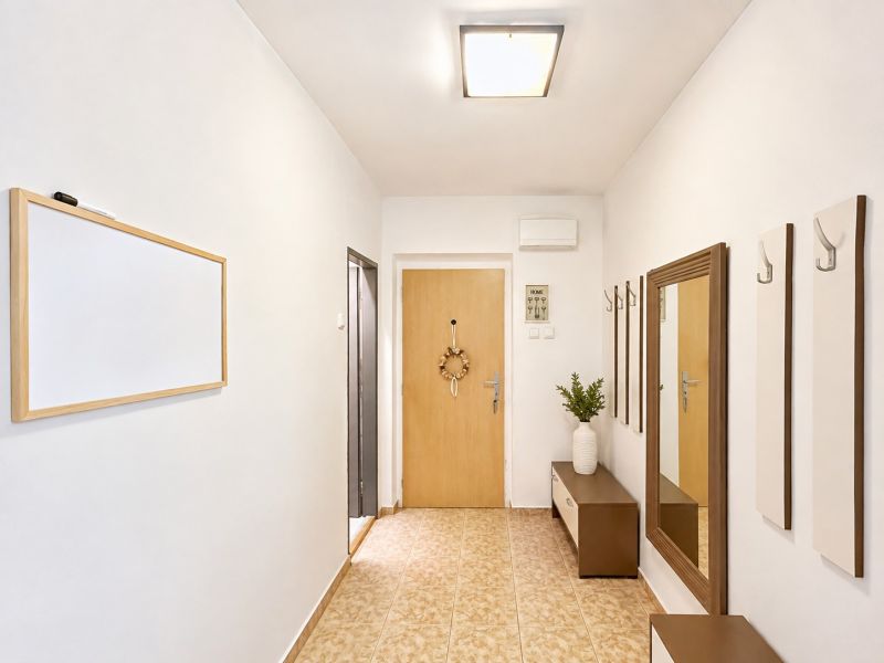 Flur mit Eingangstür, Spiegel und dekorativen Möbeln in einer 4-Zimmer-Wohnung.