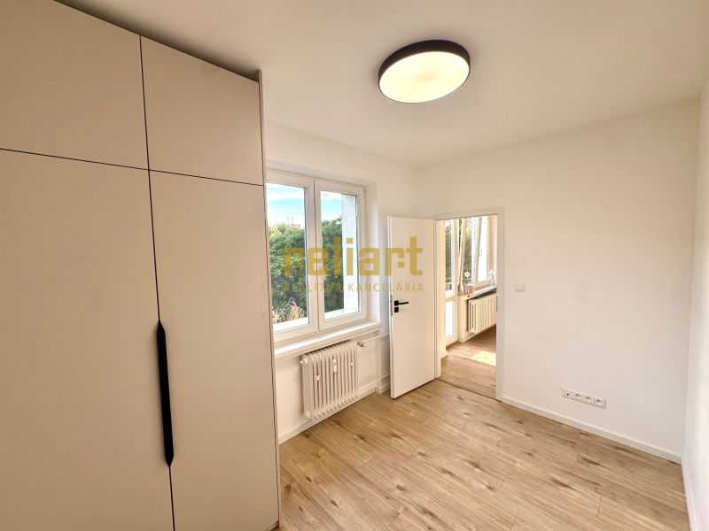 Ein Zimmer mit einem Holzboden und einem Schrank in einer 3-Zimmer-Wohnung.