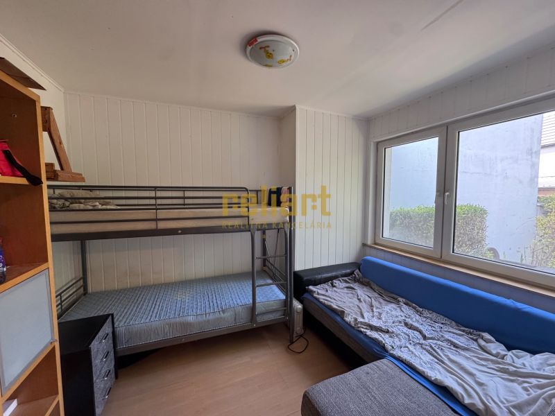 Ein Zimmer mit einem Etagenbett, einem ausziehbaren Sofa und einem Regal in einem Einfamilienhaus.
