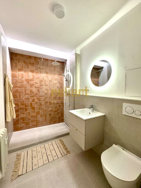 Badezimmer in einer Einzimmerwohnung mit begehbarer Dusche und rundem Spiegel.