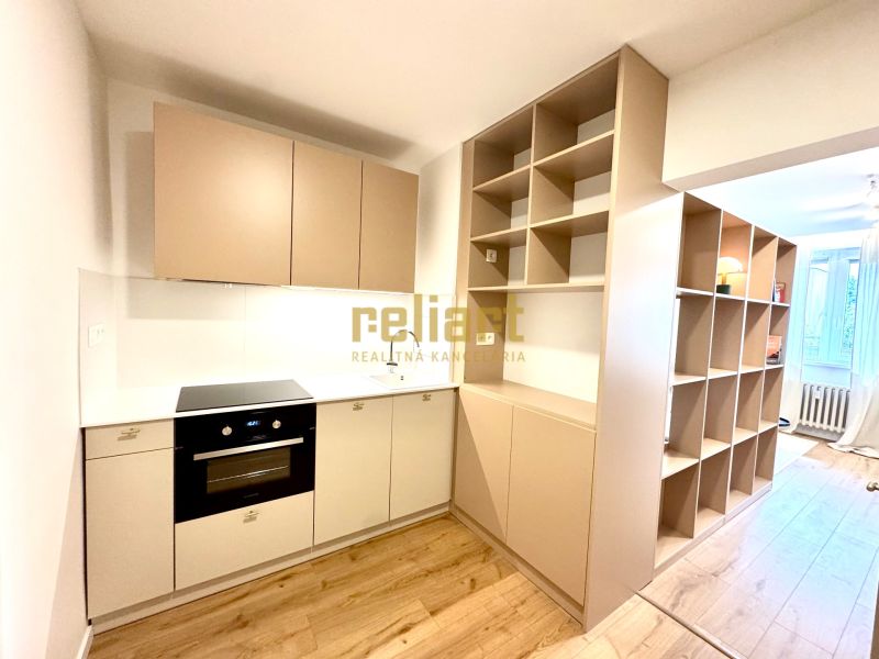 Küchenzeile mit Kochfeld und Regalen in einer Einzimmerwohnung mit Holzboden.