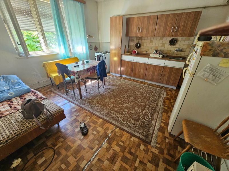 Küche in einem Einfamilienhaus mit Esstisch, Küchenzeile und Boden in Holzoptik.