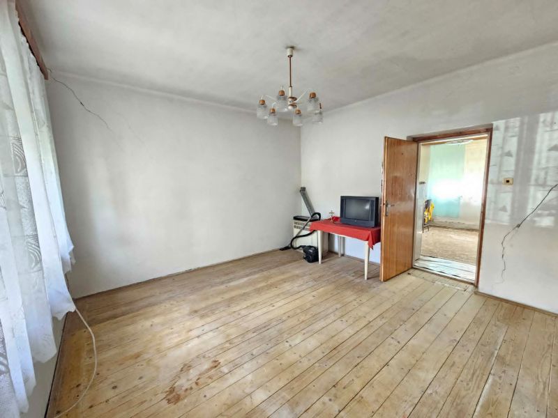 Ein Zimmer in einem Einfamilienhaus mit einem Holzboden, ein Fernseher auf einem Tisch.