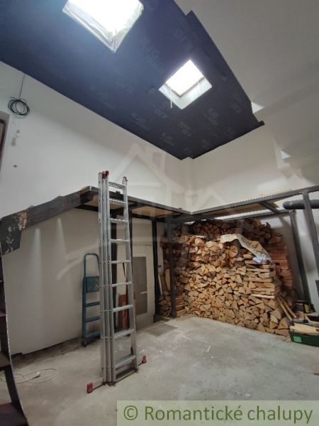 Ein Einfamilienhaus mit Holzbalken und gelagertem Holz im Innenraum.