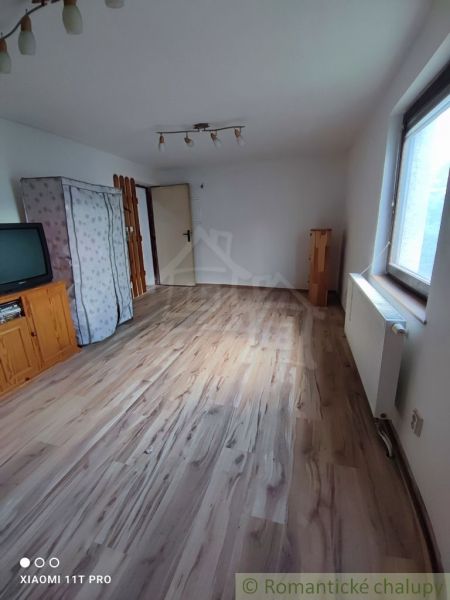 Ein Zimmer in einem Einfamilienhaus mit einem Fernseher und einem Boden in Holzoptik.