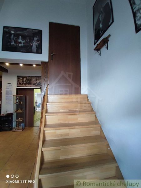 Eine Treppe mit einem Boden in Holzoptik und Kunstbildern an den Wänden in einem Einfamilienhaus.