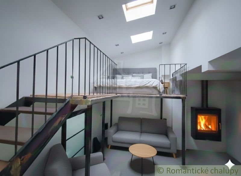 Innenraum eines Einfamilienhauses mit Galerie, Sofa, Kamin und Bett im Obergeschoss.