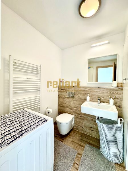 Badezimmer in einer Einzimmerwohnung mit Spiegel, Waschmaschine und Waschbecken mit Holzdekor.