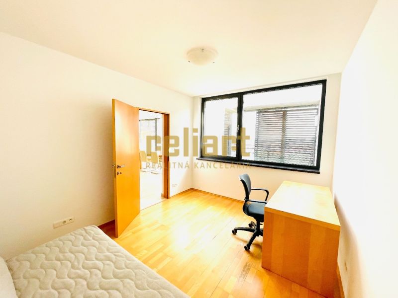 Ein Zimmer in einer 4-Zimmer-Wohnung mit einem Boden in Holzoptik, einem Schreibtisch und einem Stuhl.