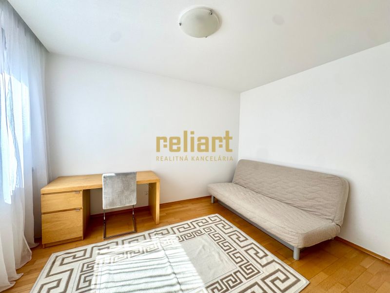 Ein Zimmer mit einem hellen Sofa, einem Schreibtisch und einem Boden mit Holzdekor in einer 4-Zimmer-Wohnung.