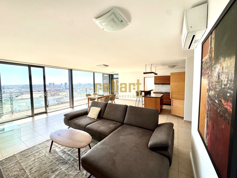 Geräumiger Wohnbereich in einer 4-Zimmer-Wohnung mit großen Fenstern und Blick auf die Stadt.