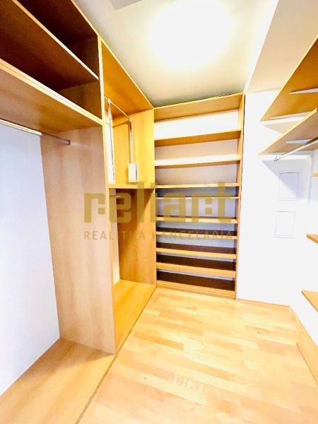 Ein Kleiderschrank mit Regalen und einem Boden in Holzdekor in einer 4-Zimmer-Wohnung.