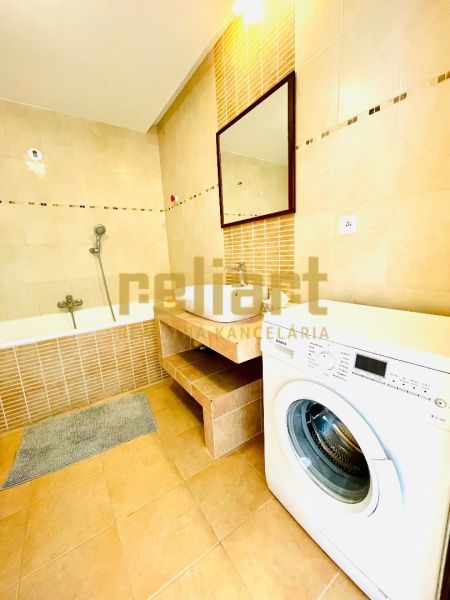 Badezimmer mit Badewanne und Waschmaschine in einer 4-Zimmer-Wohnung, Boden mit Holzdekor.