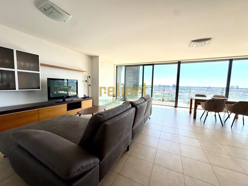 Helles Wohnzimmer mit Sofa, Fernseher und großen Fenstern, 4-Zimmer-Wohnung.