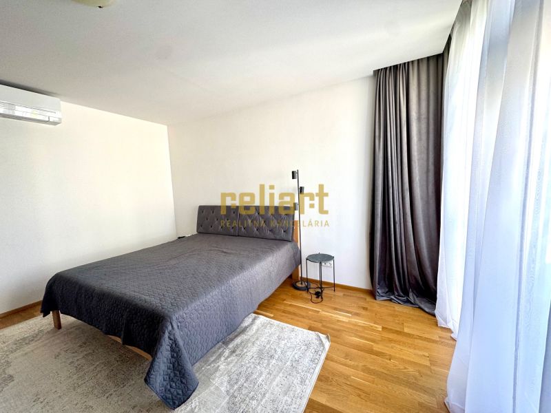 Schlafzimmer in einer 4-Zimmer-Wohnung mit Bett, Vorhängen und Boden in Holzoptik.