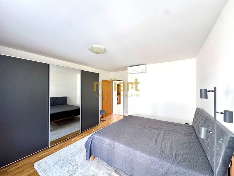 Schlafzimmer in einer 4-Zimmer-Wohnung mit einem großen Kleiderschrank und einem Boden in Holzoptik.
