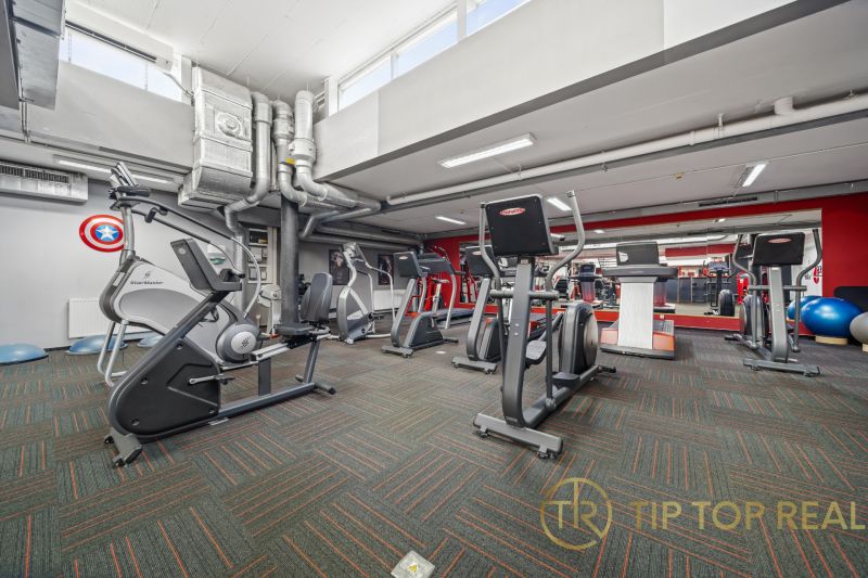 Fitnesszentrum mit Kraftgeräten, Spiegeln und Lüftungstechnik in Geschäftsräumen.