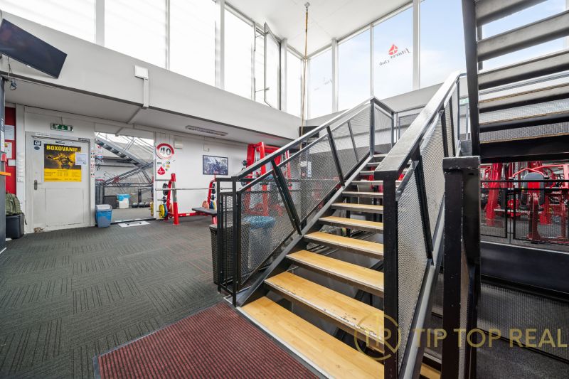 Innenraum von Geschäftsräumen mit Metalltreppe und Fitnessgeräten.