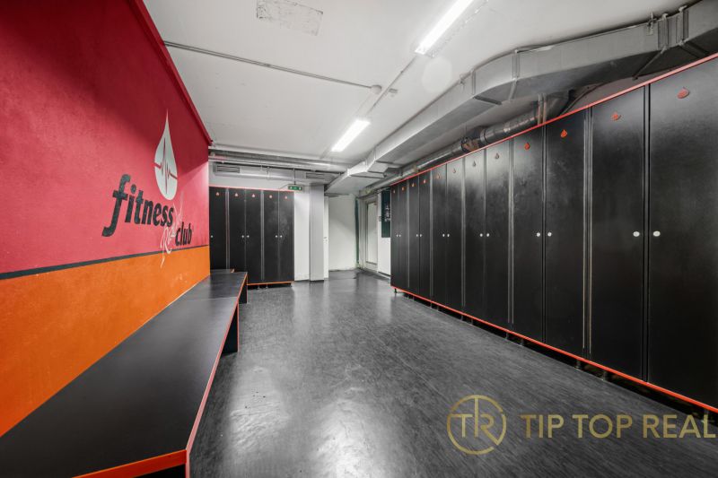 Fitness-Umkleideraum mit schwarzen Schließfächern und roter Wand in Geschäftsräumen.