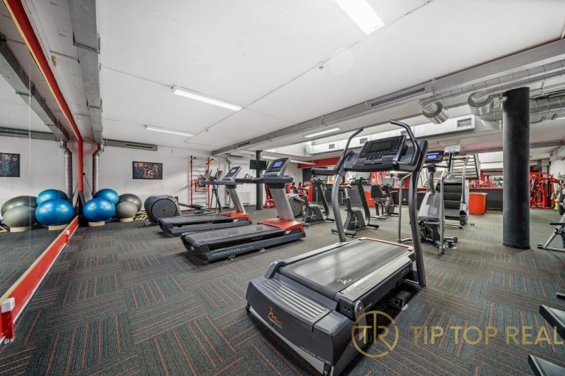 Fitnesszentrum mit Laufbändern und Trainingsgeräten in Geschäftsräumen.