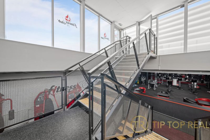 Stahltreppe in zweistöckigen Geschäftsräumen mit Fitnessgeräten.