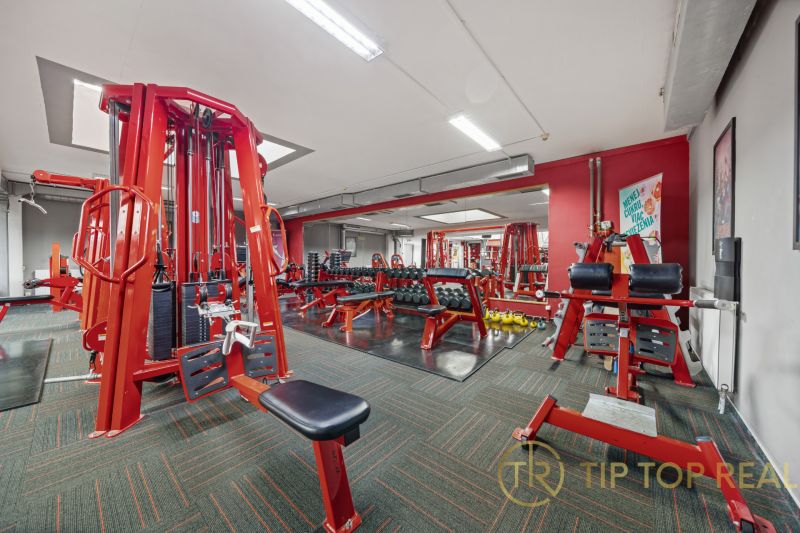Fitnesscenter mit roten Trainingsgeräten und Hanteln, Geschäftsräume.