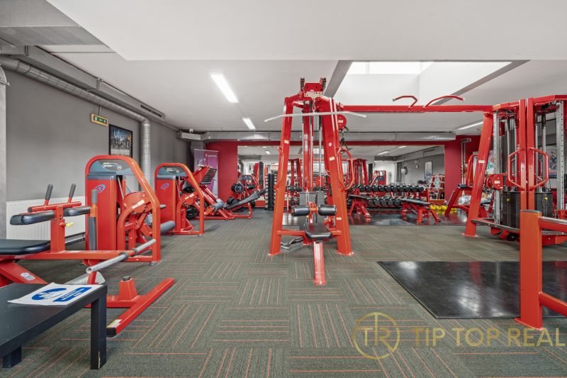 Fitnessstudio mit Kraftgeräten und Hanteln in Geschäftsräumen.