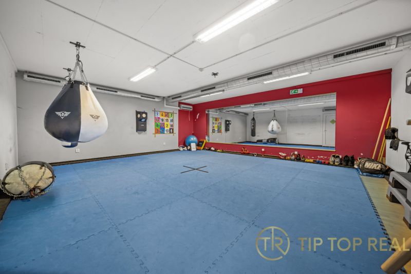 Trainingsraum mit Boxsack, Spiegeln und blauer Matte auf einem Boden mit Holzdekor.