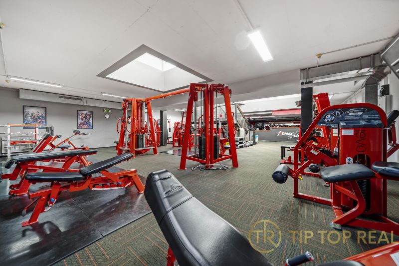 Fitnesscenter mit Kraftgeräten und roten Bänken, geeignete Geschäftsräume.