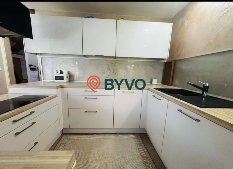 Küche in einer 3-Zimmer-Wohnung mit weißen Schränken und einer Arbeitsplatte in Holzoptik.