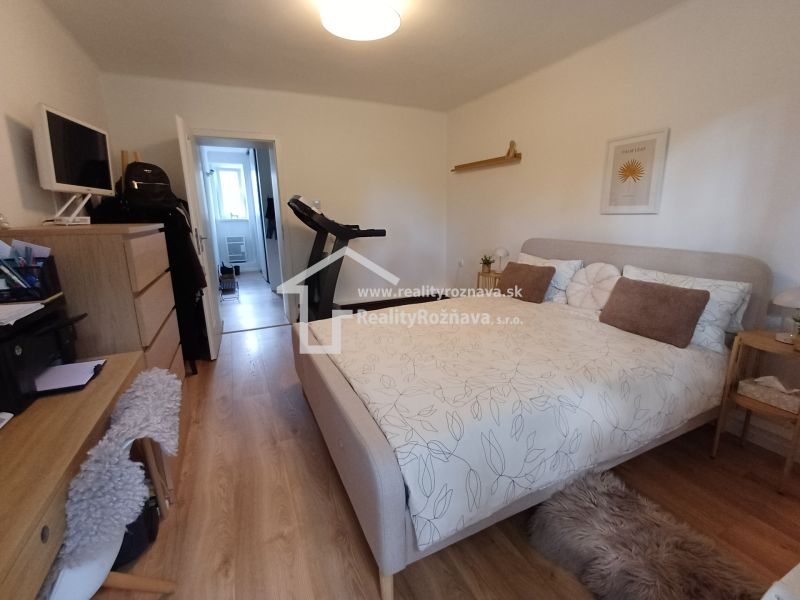 Schlafzimmer in einer 2-Zimmer-Wohnung mit Holzboden und Fitnessgerät.