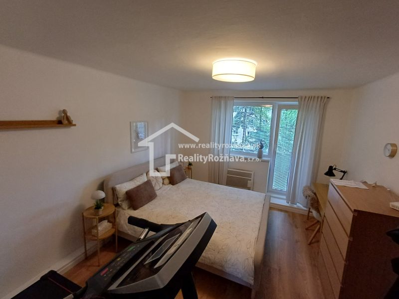 Schlafzimmer in einer 2-Zimmer-Wohnung mit Holzboden und Trainingsgerät.