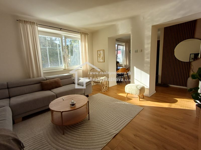 Wohnzimmer in einer Zweizimmerwohnung mit einem bequemen Sofa und einem Boden in Holzoptik.