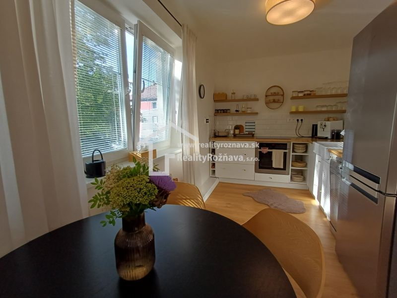 Küche in einer 2-Zimmer-Wohnung mit Holzboden, Fenstern und einem Tisch mit Blumen.