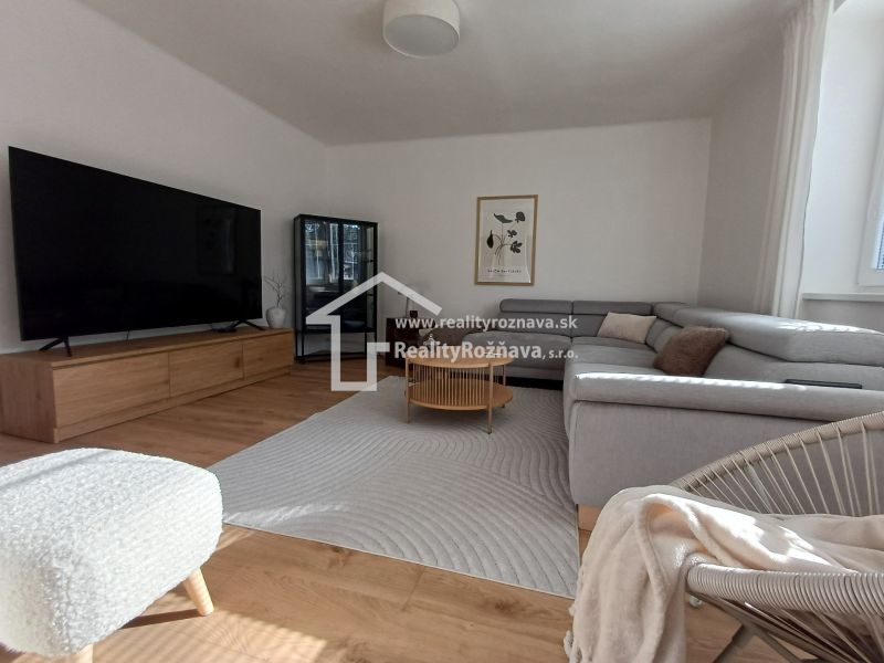 Helles Wohnzimmer mit Holzboden, Sofa und großem Fernseher in einer 2-Zimmer-Wohnung.