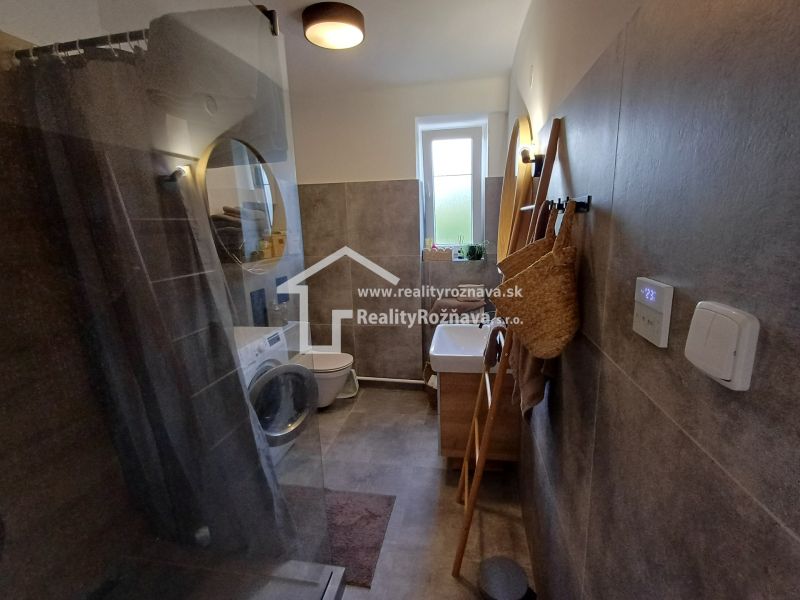 Badezimmer mit Waschmaschine und Duschkabine in einer 2-Zimmer-Wohnung.