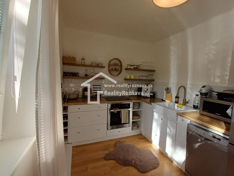 Küche in einer 2-Zimmer-Wohnung mit weißer Küchenzeile und Boden in Holzoptik.