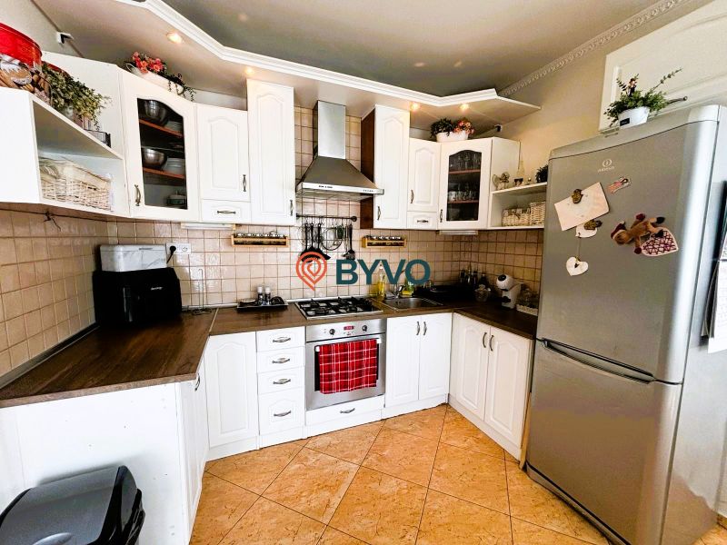 Küche in einem Einfamilienhaus mit weißen Schränken und einem Kühlschrank aus Edelstahl.