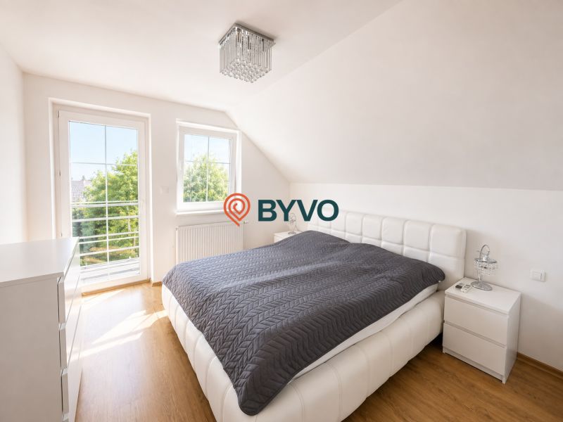Schlafzimmer im Einfamilienhaus mit großem Fenster und Boden in Holzoptik.