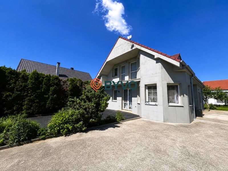 Ein Einfamilienhaus in Šamorín mit einem gepflegten Garten und einer Betonzufahrt.