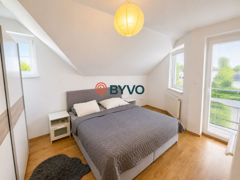 Schlafzimmer mit Dachfenstern, grauem Bett und Holzboden in einem Einfamilienhaus.