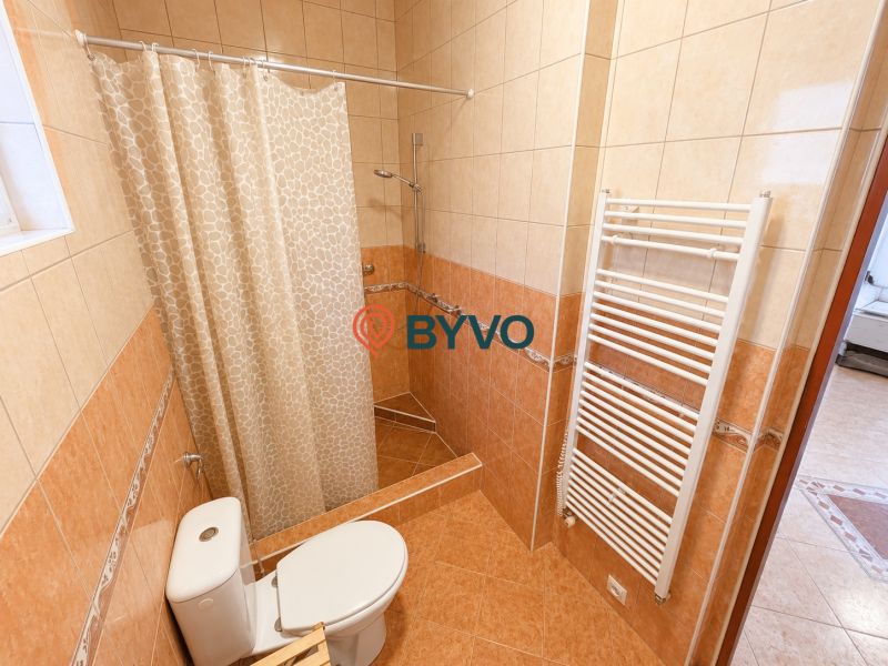 Badezimmer mit Toilette und Dusche in einem Einfamilienhaus, gefliest mit Keramikfliesen.