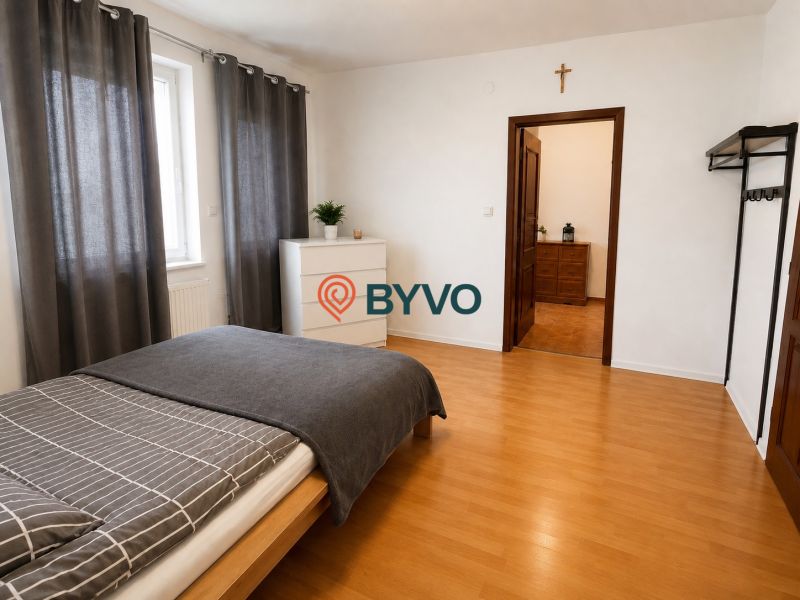 Schlafzimmer im Einfamilienhaus mit Bett, Kommode und Boden in Holzoptik.