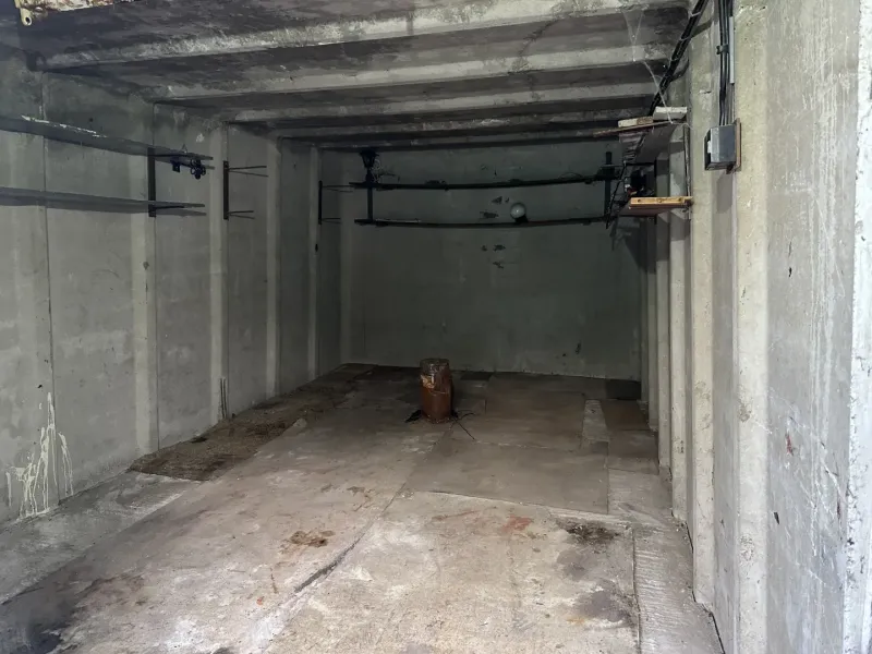 Betongarage in Bratislava - Nové Mesto mit einfachen Wänden und Lagerregalen.
