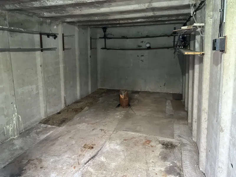Innenraum einer Garage mit Betonwänden und Regalen zur Aufbewahrung von Gegenständen.